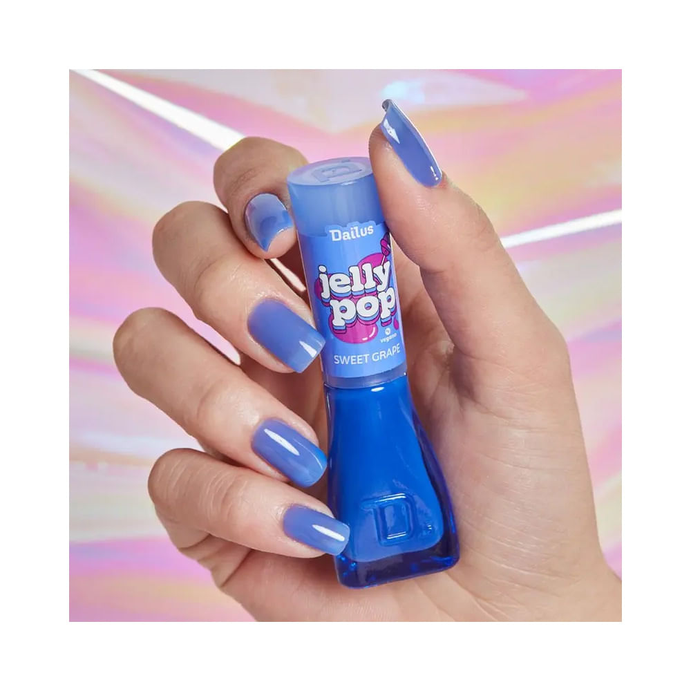 Mão segurando esmalte Dailus Jelly Pop Sweet Grape com unhas pintadas na cor violeta translúcida
